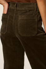 Load image into Gallery viewer, Close-up back view of a woman wearing dark brown corduroy pants, showing the waistband, belt loops, and back pockets against a plain light background.