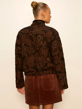 Load image into Gallery viewer, A woman shown from the back wearing a dark brown paisley patterned jacket with a high mock neck and a brown mini skirt, set against a plain off-white background.