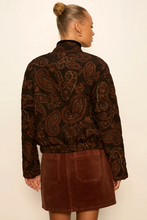 Load image into Gallery viewer, A woman shown from the back wearing a dark brown paisley patterned jacket with a high mock neck and a brown mini skirt, set against a plain off-white background.